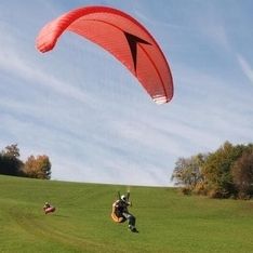 Paragleitsprung auf unserem eigenen Trainingsgelände mit Wiese und Bäumen im Hintergrund
