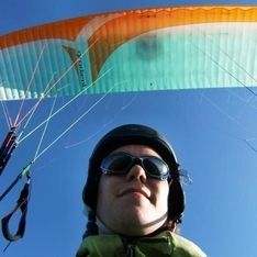 Ein Gesicht eines Paragleiters im Flug vor blauem Himmel im Hintergrund