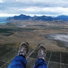Bild von Füßen eines Paragleiters beim Fliegen über Feldern und Bergen