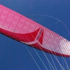 Ein roter Gleitschirm in Nahaufnahme vor blauem Himmel im Hintergrund