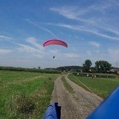 Ein roter Paragleitschirm wird von einem blauen Auto gezogen