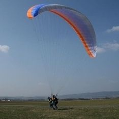 Ein Paragleiter auf einer Wiese vor blauem Himmel im Hintergrund