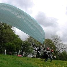 Ein Doppelsitzer mit offenem Schirm auf einer Wiese beim Starten