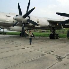 Eine Person vor einem motorisierten Flieger auf einer Flugbahn